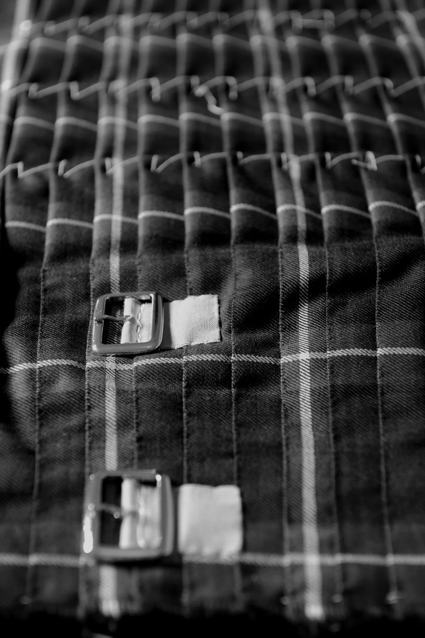 Two leather straps and buckles on a hand-sewn tartan kilt